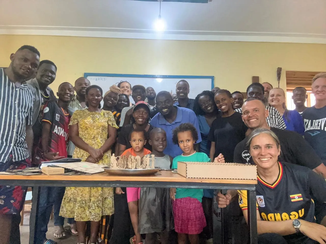 A large group of adults and children posing together in a room around a table.
