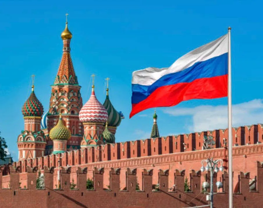 Saint Basil's Cathedral with a Russian flag against a blue sky.