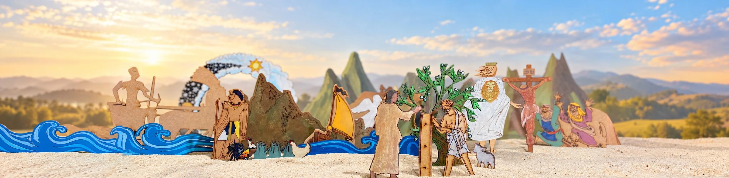 Flat painted wooden figures standing in pale sand: blue waves and a boat with a yellow sail, green mountains, an olive tree with two figures beside it, a figure in a white cloak with a lion on its back and a wooden cross, with a low sun, clouds and distant hills behind.